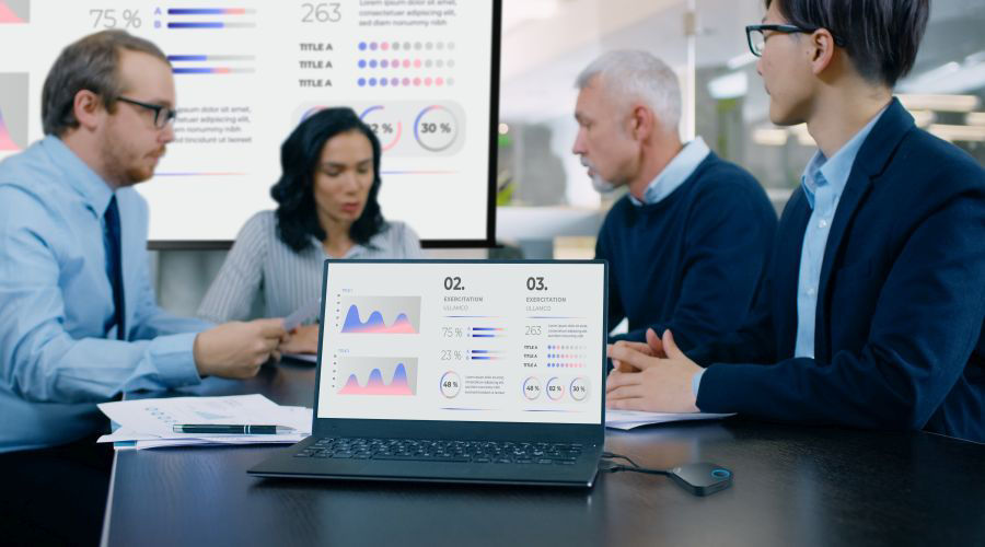 In the Meeting Room Laptop with Green Chroma Key Screen on the Conference Table. In the Background Business People Have Important Discussion.