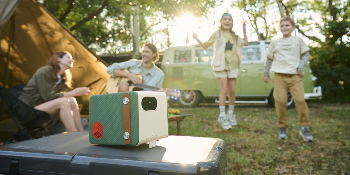 Family having a great time outdoor with a portable projector by a van