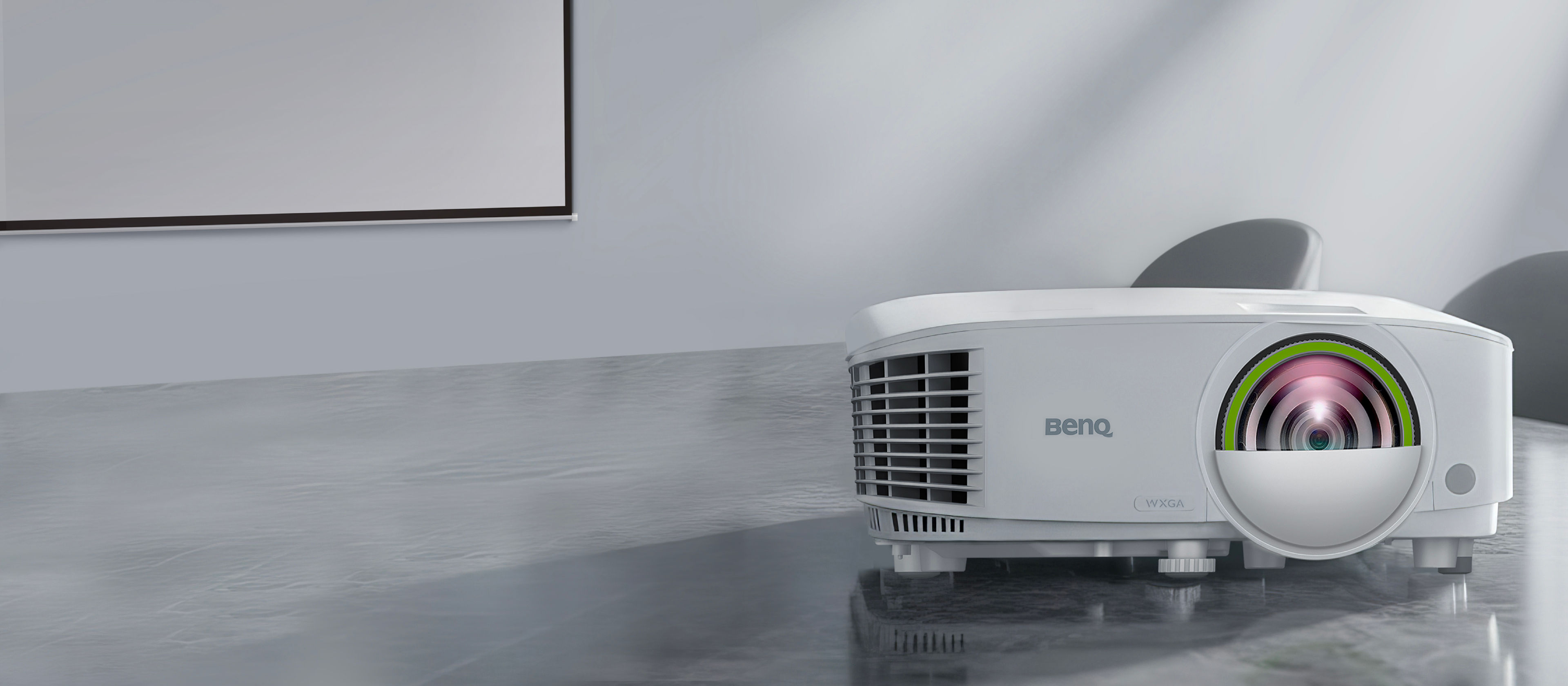 A white BenQ EW710ST short throw smart business projector on a grey table in a bright modern office, featuring 3600AL brightness and wireless projection for innovative workplace solutions.