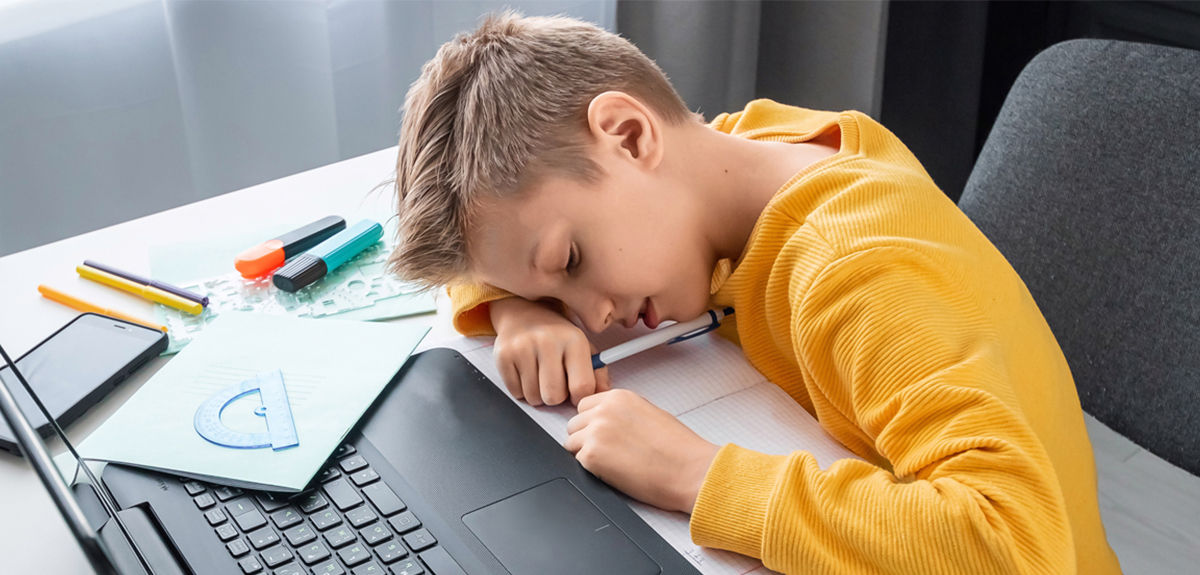 Student learning remotely from his laptop bored as he cannot understand what the teacher is saying because of poor audio quality