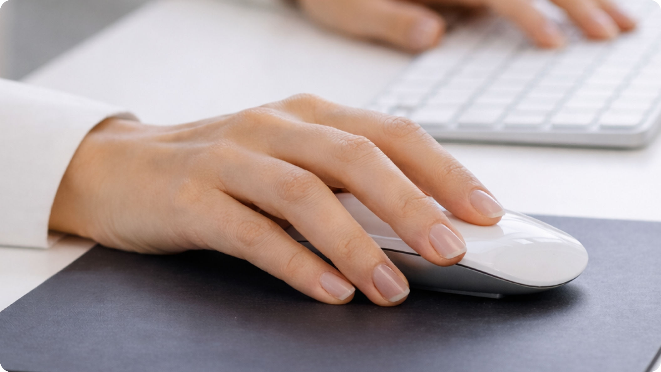 Hand using a Magic Mouse to illustrate how its flat, low-profile shape can provide limited support during long periods of use.