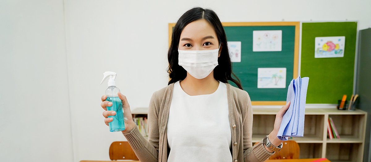 teacher disinfecting a classroom to ensure student safety in the post-pandemic school reality