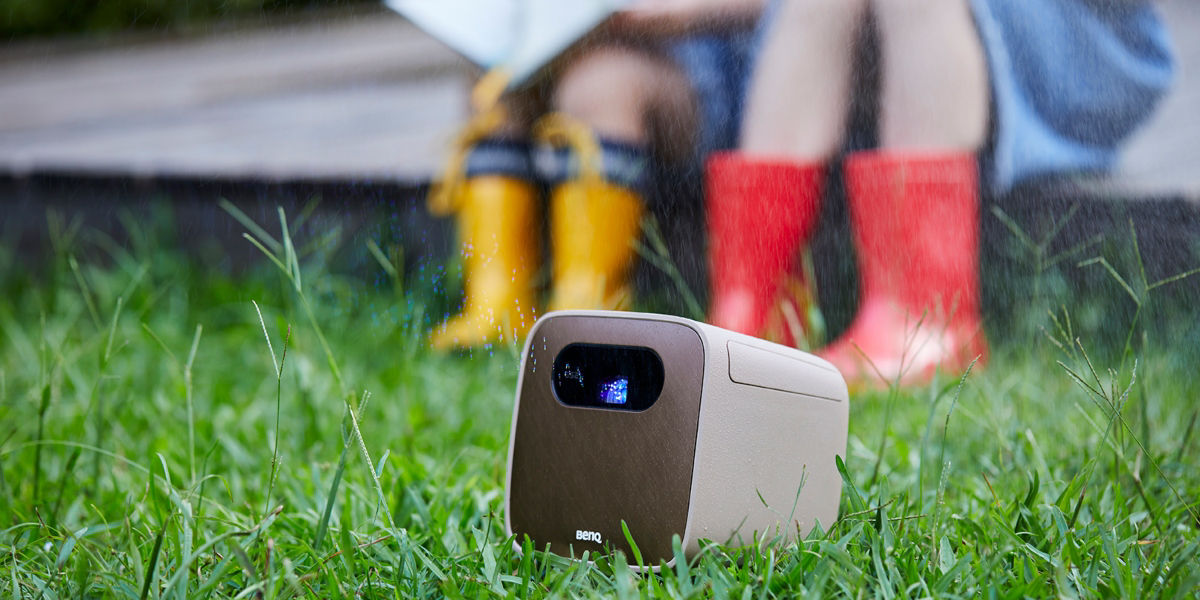 an outdoor projector projecting image in a yard with rain in the background