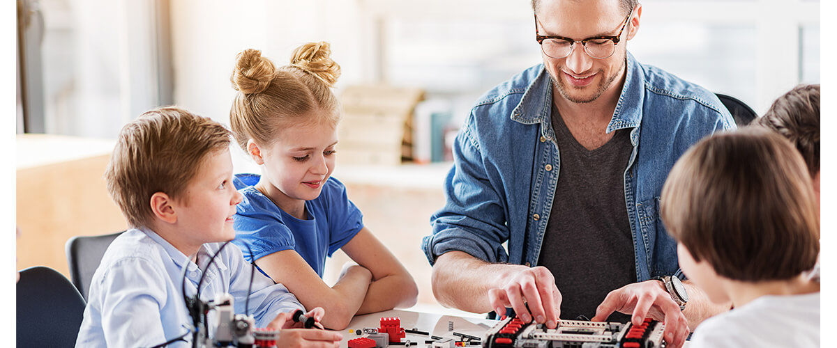 Teacher making a machine from building blocks together with his students