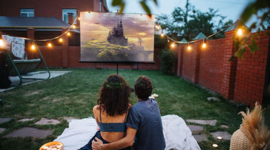 A couple preparing to watch movies on a projector in the backyard 