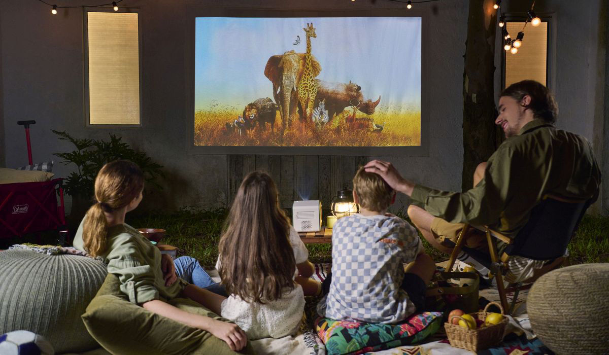 A family of four watching a movie in the backyard using GS50 portable projector