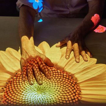 Une femme âgée interagit avec un contenu projeté sur table