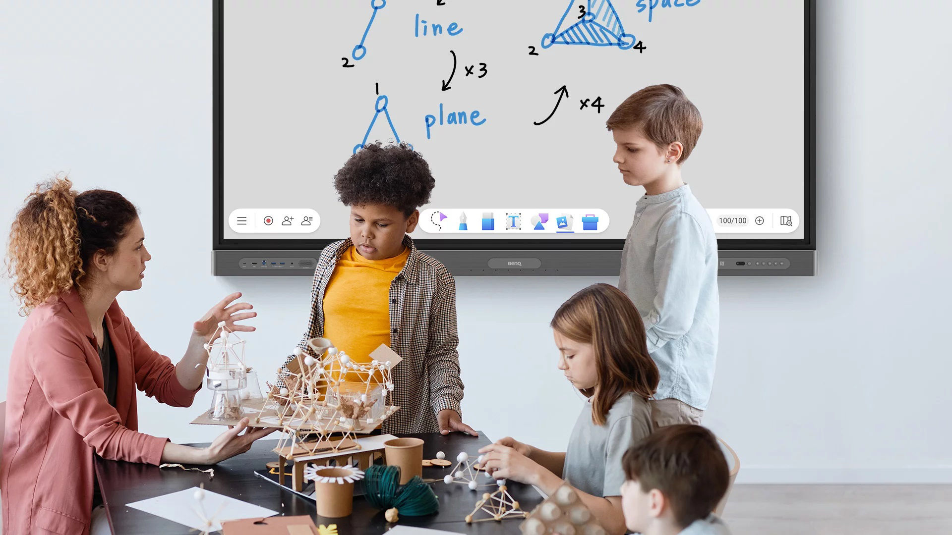 A teacher is teaching physics in front of a digital board