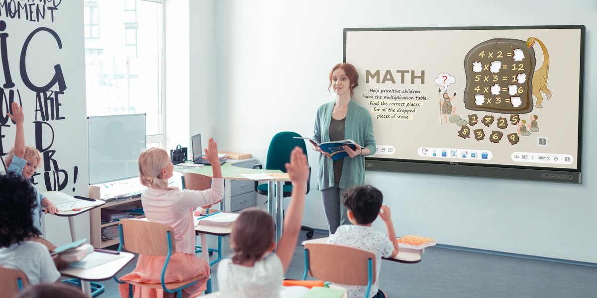 Teacher using BenQ interactive display to teach maths to students who are engaged and participate actively, raise their hands to volunteer to come to the board
