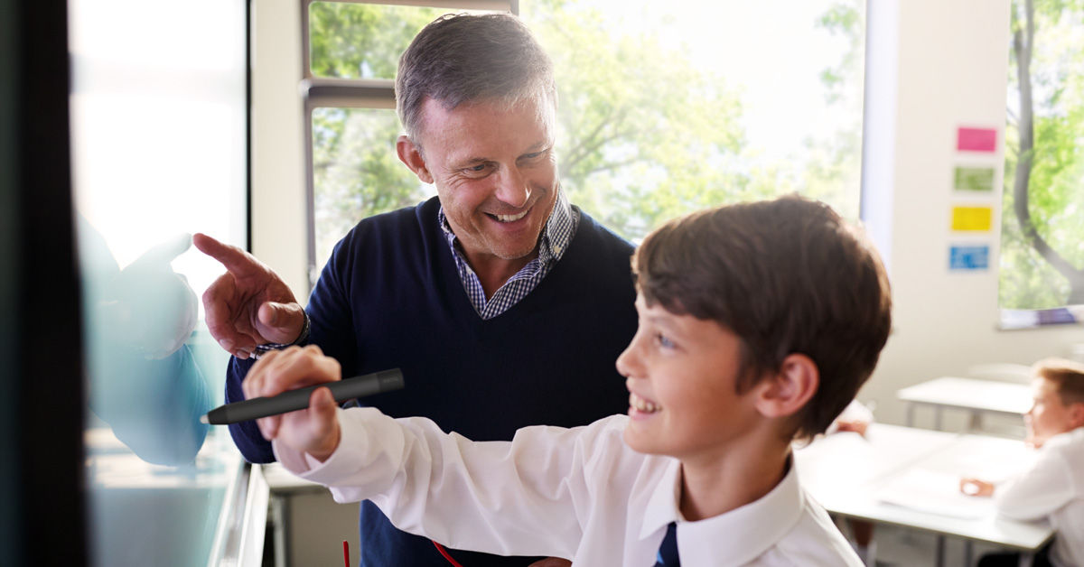 teacher instructing student to use BenQ germ-resistant pen to write on BenQ interactive display in a classroom