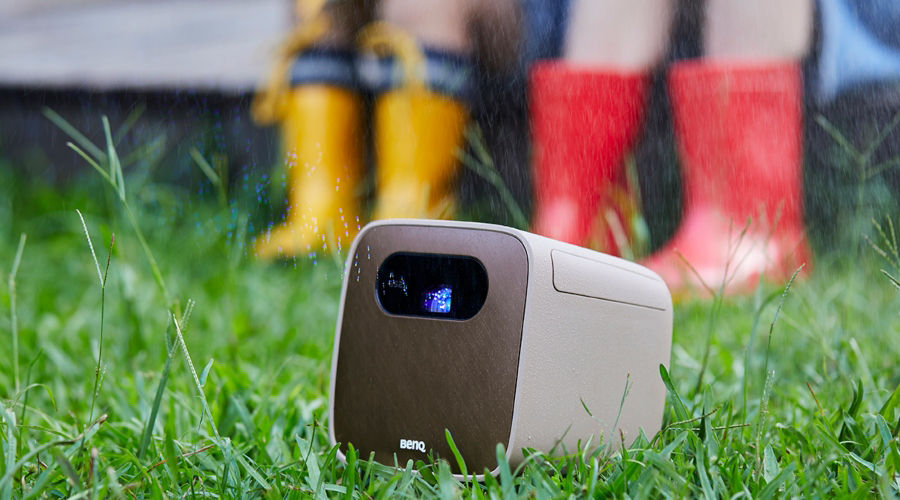 An outdoor projector projecting image in a yard with rain in the background