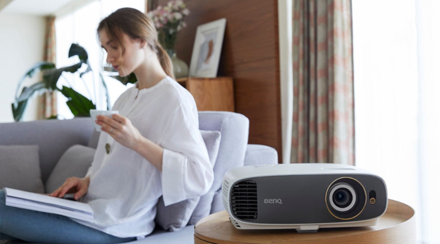 A woman is working from home while enjoying her free time with a projector for visual entertainment.