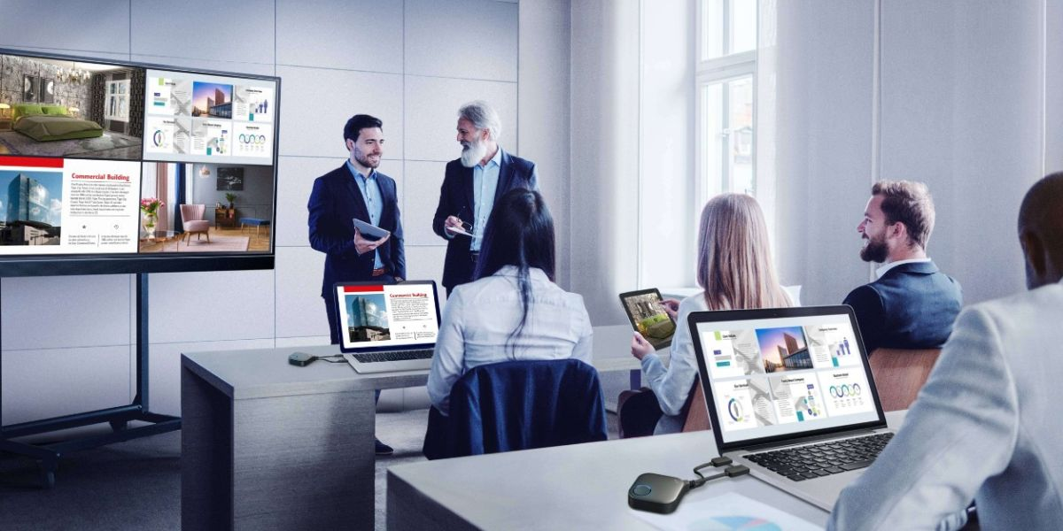 The group of people is having a meeting with split screens on the display.