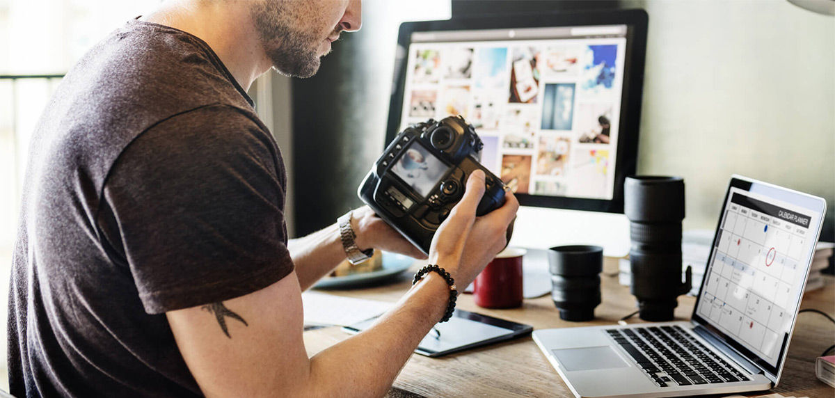 The photographer is checking the image in the camera and prepare to do photo editing by using his laptop and the professional monitor.