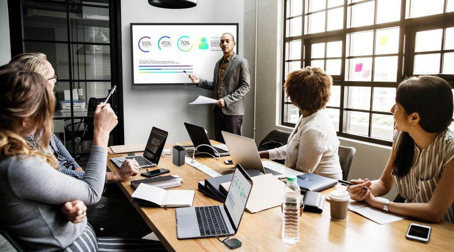 A group of office workers are using Macbook to wirelessly share content in the meeting.