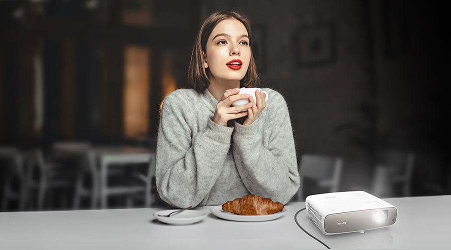 A woman is watching virtual cinema film in her place with BenQ short-throw projector W2700.